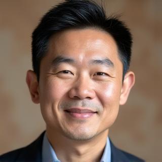 Professional headshot of David Kim, a meditation teacher, with a calm, reassuring demeanor. The background is subtly blurred to emphasize his portrait, conveying a sense of grounded professionalism.